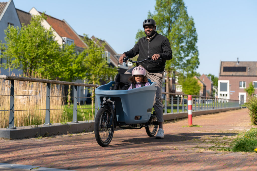 Father and daughter wearing helmets on a Dolly Joy cargo bike